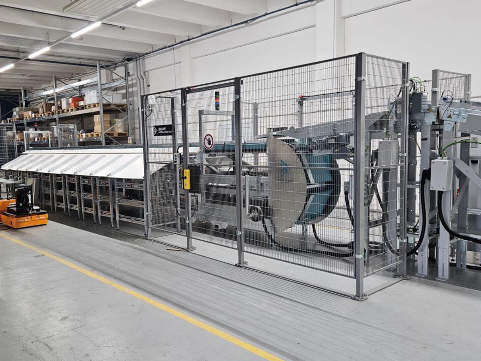 Industrial Machinery in a Manufacturing Facility A modern industrial machine behind a safety fence in a manufacturing environment.