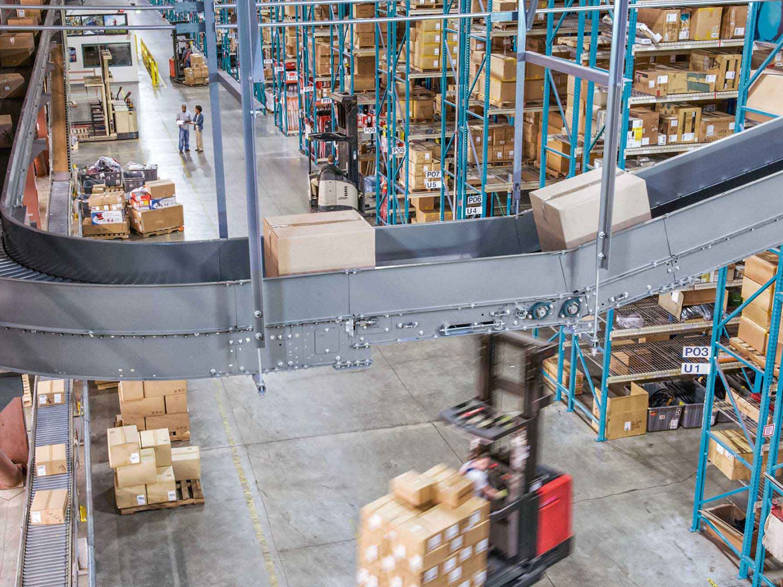 Modern Warehouse With Automated Conveyor System Aerial view of a busy warehouse featuring an automated conveyor system, with workers and forklifts moving packages.