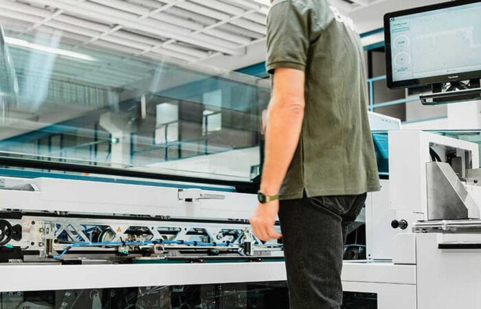 A technician interacts with high-tech printing machinery in a modern facility.