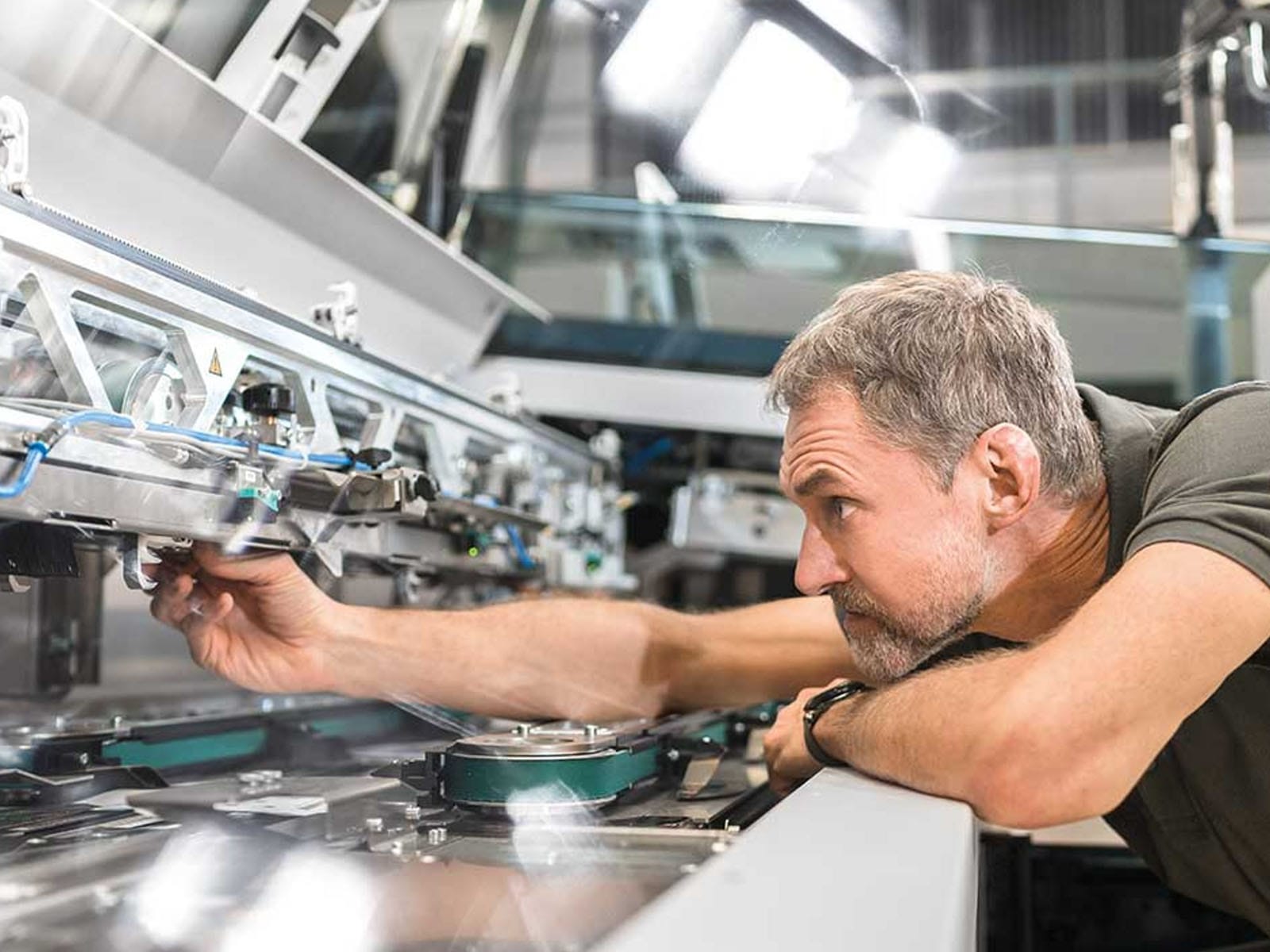 Skilled Technician Working on Precision Machinery A male technician inspecting and adjusting a high-tech machine in an industrial setting.
