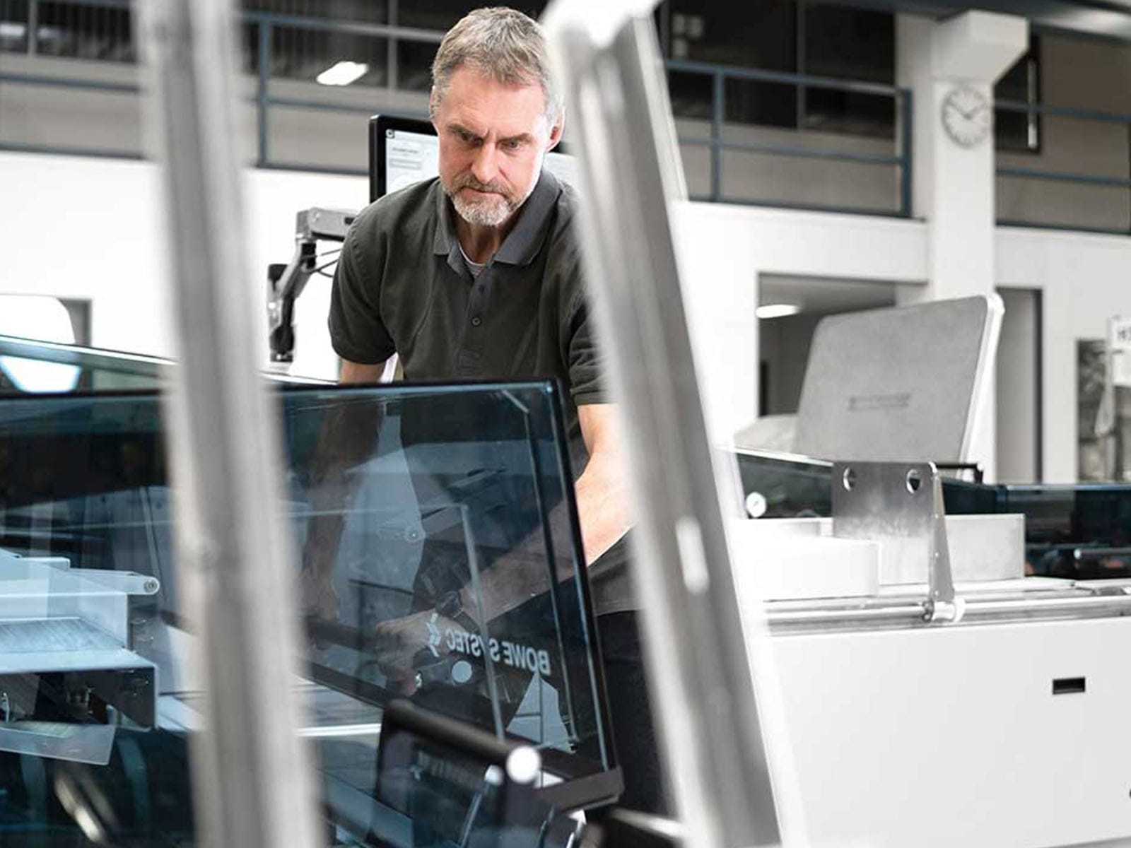 Manufacturing Worker Inspecting Glass Panel A focused manufacturing worker examining a glass panel in a modern industrial setting.